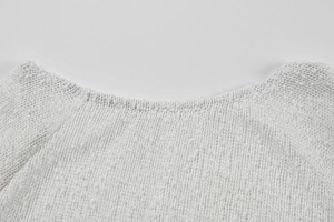 Close-up of white hollow-out knit neckline with textured granular yarn details
