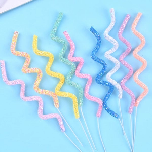 Colorful glittery spiral candle toppers in various colors arranged on a blue background