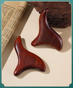 Sandalwood triangle massager set on vintage book pages for meridian pressure therapy