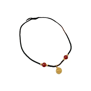 Modern red agate bead necklace with a gold Fu character pendant on black woven cord