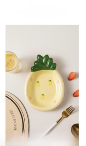 Detail of pineapple-shaped ceramic plate with cute fruit patterns and yellow finish