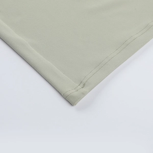 Detailed close-up showing double-needle flat stitching on a light green knitted dress hem
