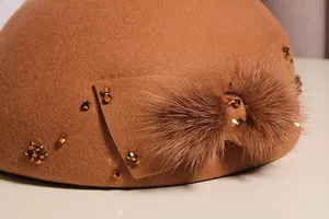 Detailed view of brown wool beret featuring a plush bow and amber bead accents