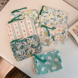 Detailed view of six floral cotton coin purses with simple wish labels and green zippers