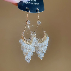 Macro view of gold crystal tassel earrings with sparkling teardrop beads and metal hooks