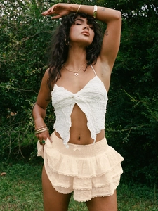 Détail du haut dos nu blanc bohème et jupe en dentelle à plusieurs niveaux beige en forêt