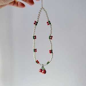 Close-up of pearl phone strap featuring cute 3D cherry beads and glossy cherry pendant