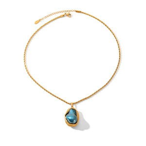Detailed top-down shot of a gold twist chain necklace with a blue baroque pearl pendant
