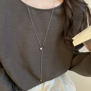 Detail of silver long chain necklace with black and white spotted bead on a model