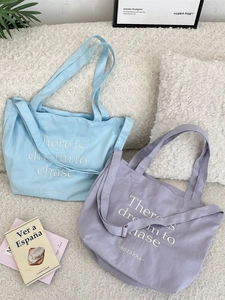 Blue and purple canvas tote bags with dream lettering on white fleece background