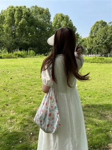 Floral cotton tote bag with soft pink flowers shown on model in a summer outdoor setting