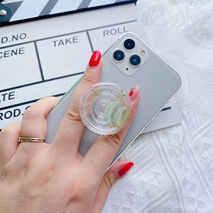 Detail shot of a clear glitter phone grip featuring gold stars and a green planet design