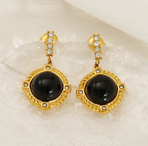 Détail de boucles d'oreilles rétro dorées avec pierre d'agate noire et zircons brillants