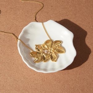 Macro detail of gold double flower pendant necklace on a decorative shell tray