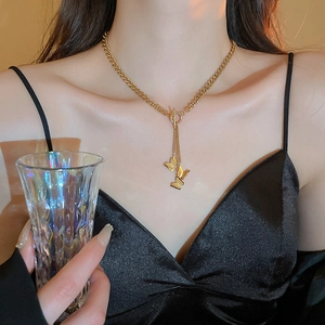 Dettaglio della collana dorata a farfalla con chiusura OT indossata da una modella elegante