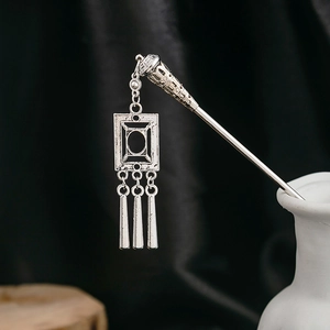 Detail of silver vintage hairpin with hollow flower design and fringe tassel accents