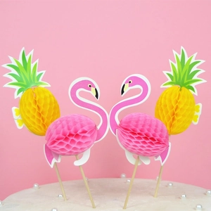 Macro detail of honeycomb paper flamingo and pineapple cake toppers on wooden sticks