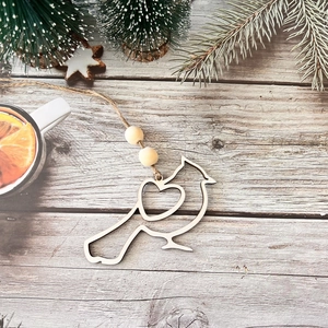 Detail of bird-shaped wooden ornament with heart cutout and beads on festive wood background