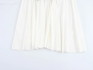 Detailaufnahme des eleganten Plissee-Saums am weißen ärmellosen Maxikleid