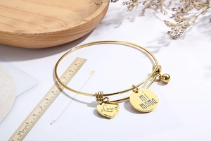 Détail de breloques cœur et cercle dorées avec gravure Love mi mama sur bracelet