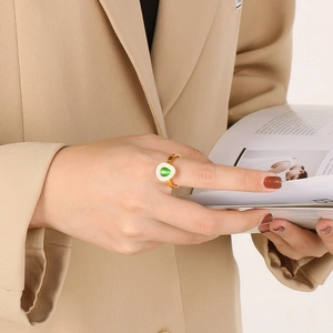 Detailed view of a gold-plated ring with a teardrop green stone on a female model