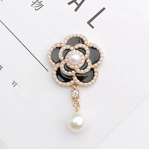 Detailed view of camellia pendant with black enamel petals and faux pearl accents