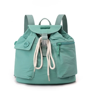 Detail of mint green nylon backpack showing drawstring closure and flap pocket with stitching