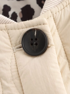 Detail of beige quilted jacket featuring a brown marbled button and ribbed collar texture