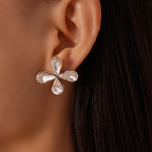 Close-up of a sparkling glass teardrop flower stud earring worn on ear with silver prongs