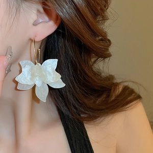 Close-up of a large white resin flower earring with a pearl luster finish on a model