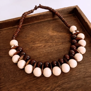 Dettaglio di collana etnica in legno con perle color crema e inserti in guscio di cocco