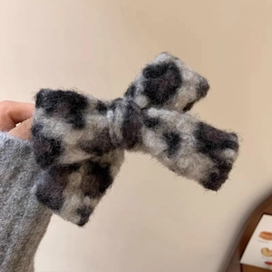 Détail du nœud papillon en peluche léopard montrant la texture douce de la pince à cheveux