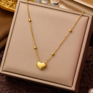 Macro shot of gold heart pendant and beaded chain on a luxury jewelry box display