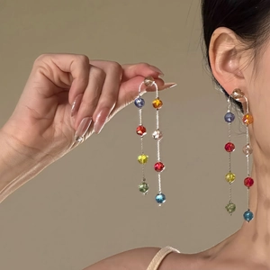 Close-up detail of long tassel earrings featuring vibrant multi-colored glass beads.