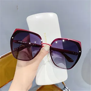 Detail of dark red cat eye sunglasses with purple gradient lenses and white hard case