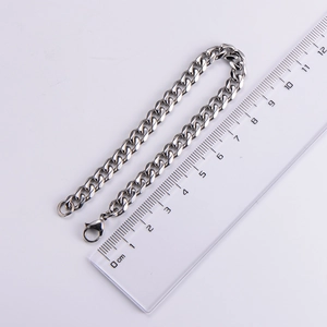 Macro shot of a 7mm silver Cuban link bracelet being measured with a metric ruler