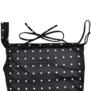 Detailed close-up of a black polka dot dress featuring thin straps and a decorative bow tie