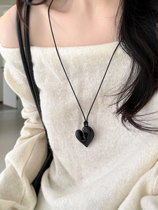 Dettaglio di un ciondolo a cuore nero effetto fuso su una collana minimalista in cordino