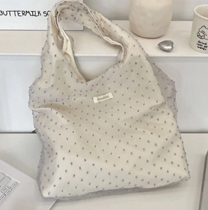 Macro view of cream organza tote bag featuring grey embroidered polka dots and label