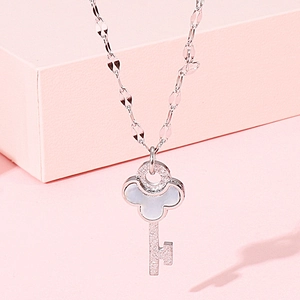 Macro shot of silver key pendant necklace with white shell inlay and floral detail
