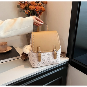 Détail d'un sac à dos camel et crème avec imprimés ours et breloque peluche en décor réel