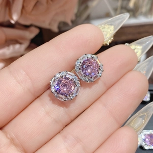 Macro detail of hand-held pink gemstone earrings with butterfly bow and halo setting