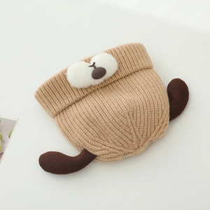 Detail of baby knitted hat with cute dog ear design and soft khaki wool texture