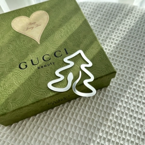 Close-up of silver Christmas tree charm on luxury green embossed gift box packaging