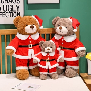 Drei Größen Weihnachts-Teddybären in roten Weihnachtsmann-Outfits auf Holzgrund