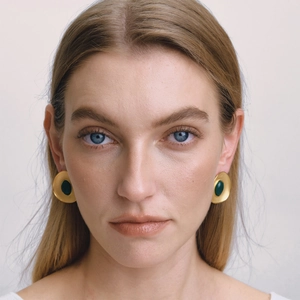 Close-up of elegant gold stainless steel earrings with dark green resin inlay on model
