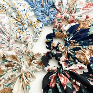 Flat lay of colorful floral scrunchies with long ribbons on a white background