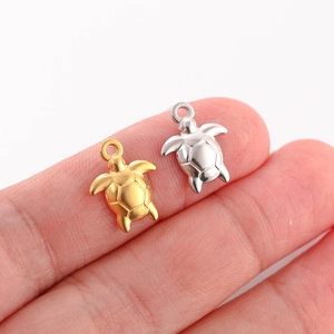Gold and silver sea turtle pendants on fingers showing size for DIY jewelry making