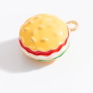 Vue détaillée du pendentif burger en métal doré avec couches d'émail multicolores vibrantes