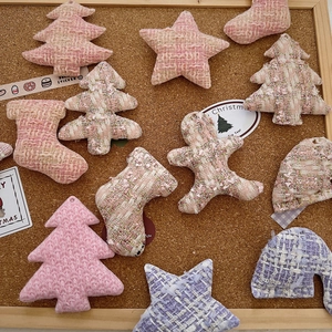 Macro shot of tweed Christmas tree and star ornaments on a warm cork background